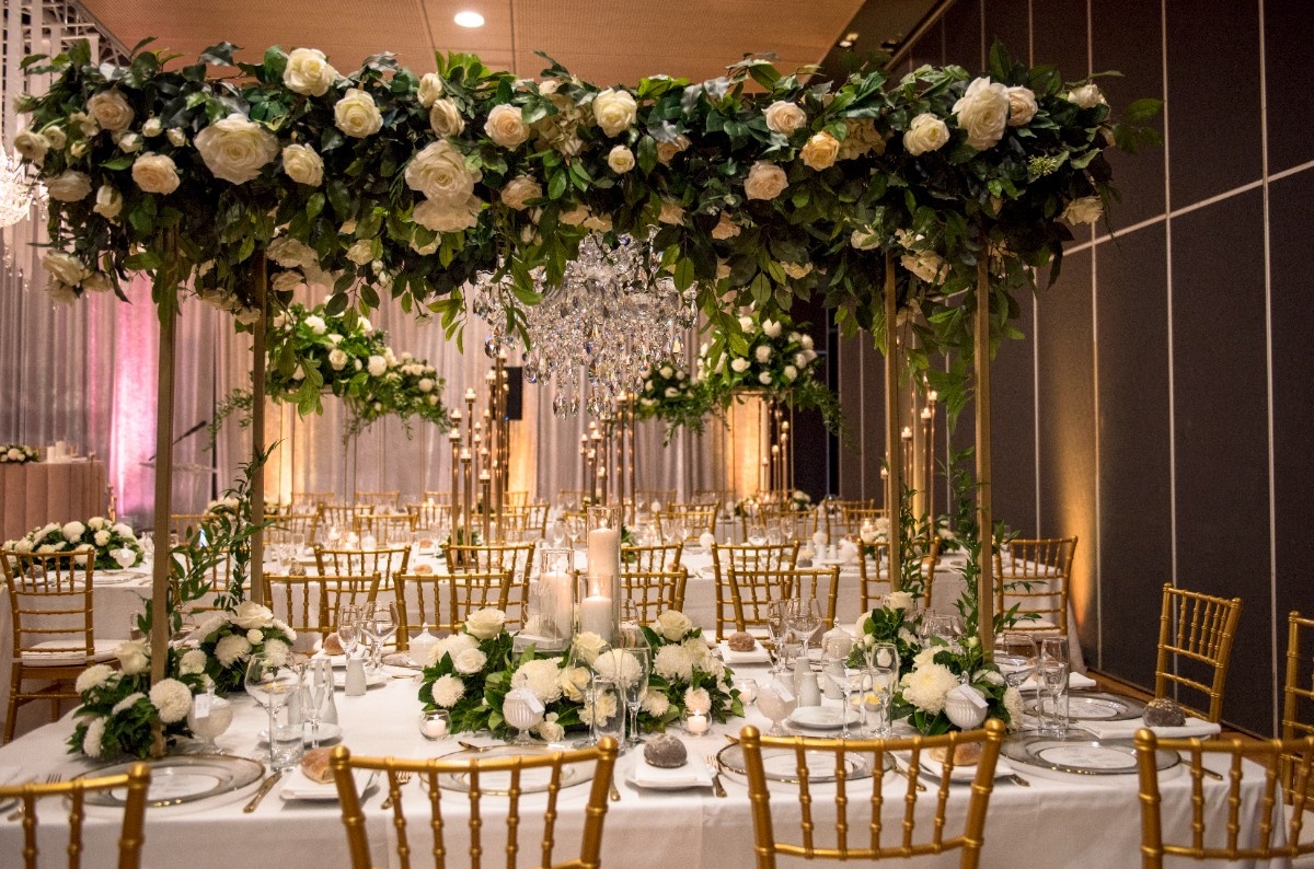 Wedding banquet tables beneath white floral arrangements in Heritage Hall